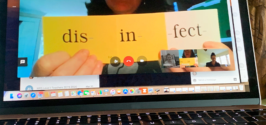 A virtual meeting screen shows a person holding three cards with the text dis- on a yellow card, in- on an orange card, and fect on a yellow card. Participants are visible in small video call thumbnails.