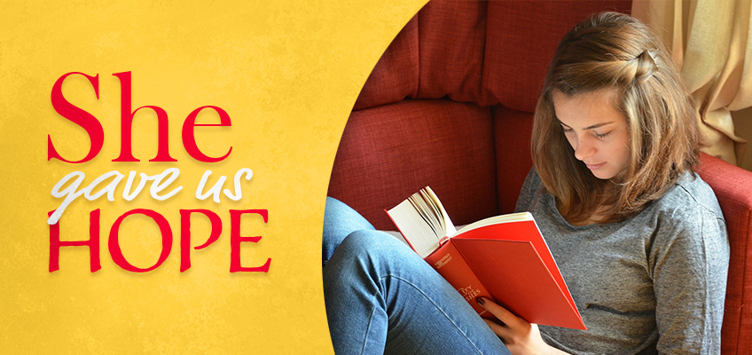 A woman with long brown hair sits comfortably on a red sofa, reading a book with a red cover. The background is yellow, with the text She gave us HOPE in red and white.