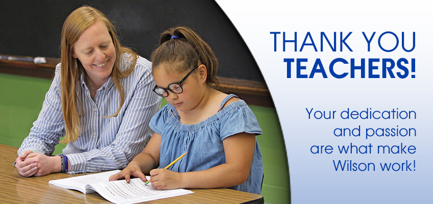 A teacher with red hair sits beside a young girl wearing glasses, helping her with schoolwork at a table. The text reads THANK YOU TEACHERS! Your dedication and passion are what make Wilson work!.