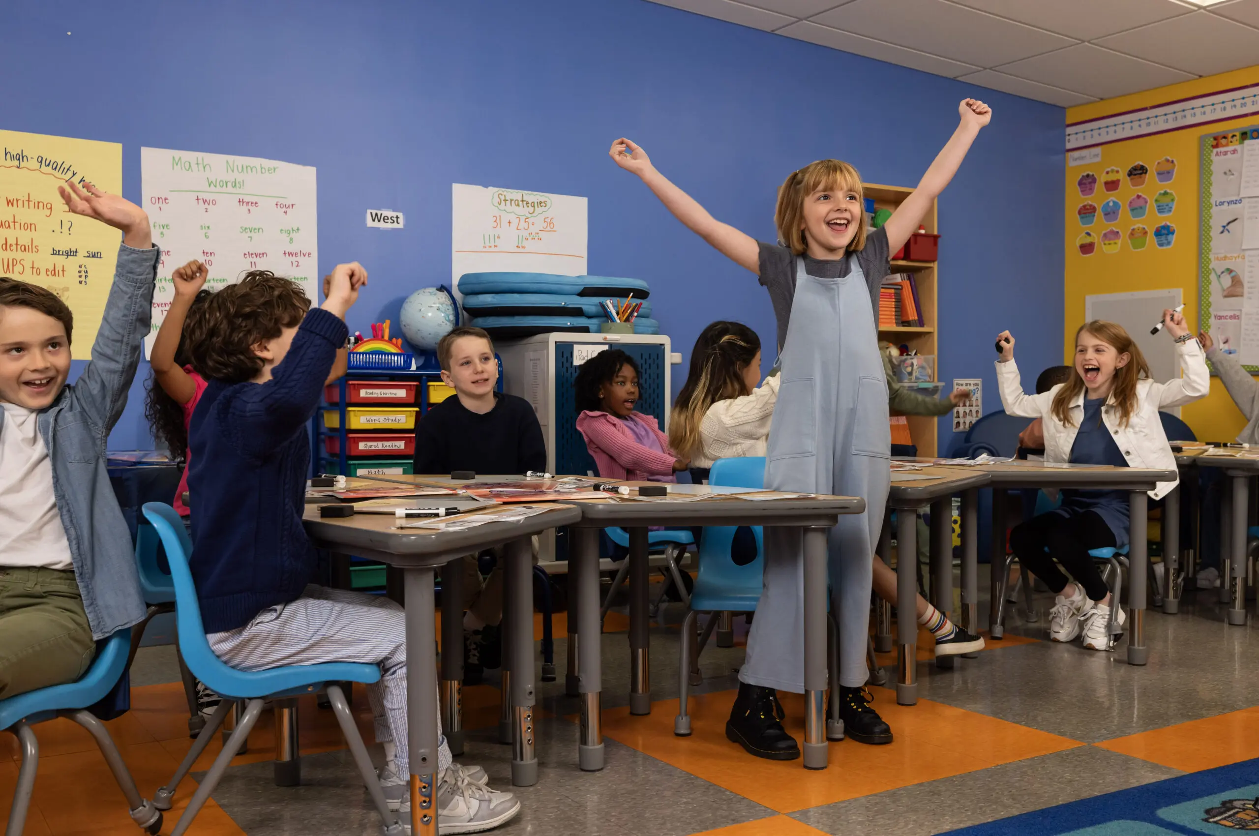 Enthusiastic Fundations K-3 students celebrate in their classroom, arms raised in excitement.