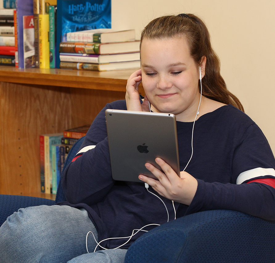 Young student using a tablet and headphones to hear content