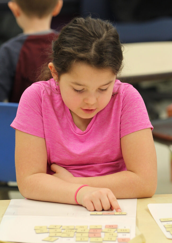 Young girl building word with magnetic letter tiles