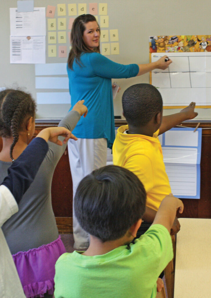 Fundations teacher writing the letter "t" on the writing grid while students skywrite