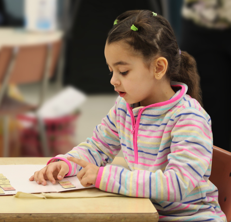 Young girl building a word using magnetic letter tiles