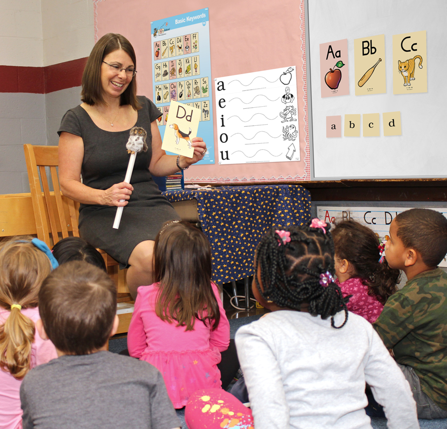 Fundations Pre-K teacher holding up D sound card and baby echo puppet