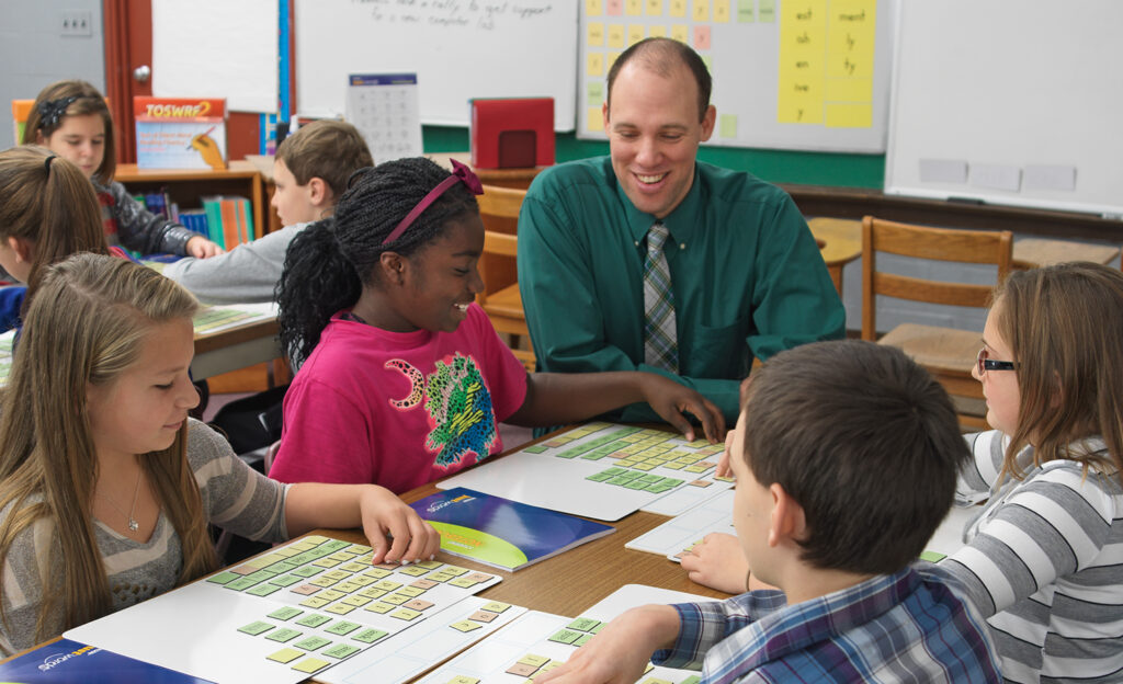 A teacher with students using magnetic letter tiles to build words