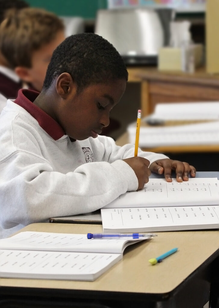 Student holding pencil while writing in a book