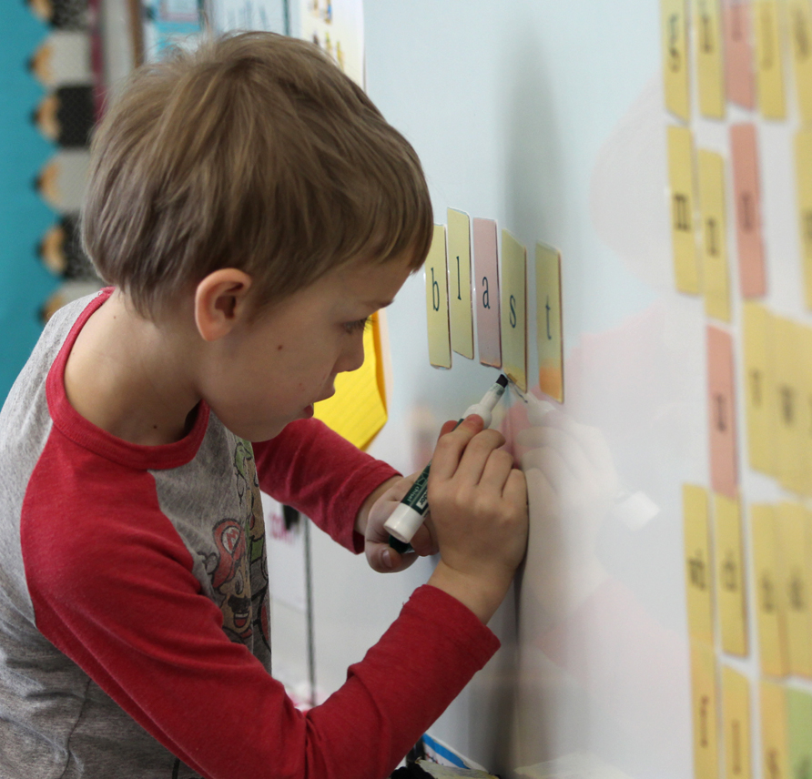 Young student marking up sound cards on a white board with a dry erase marker