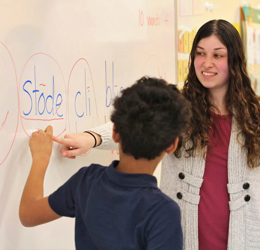 Teacher pointing to board as student marks up the word stode