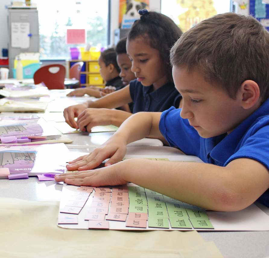 Students arranging their magnetic letter tiles on their letter boards.