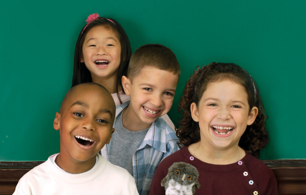 Four giggling fundations students holding a baby echo the owl puppet