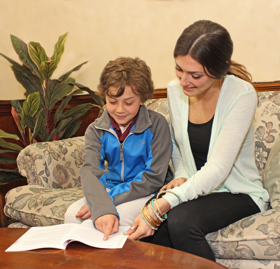 A parent sitting next to their child reading