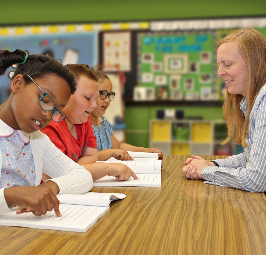 WRS teacher watching 3 students silently read from their WRS Student Readers