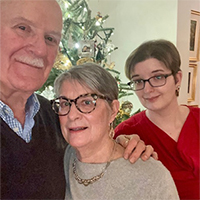 Man and two women posing together in front of holiday decorations