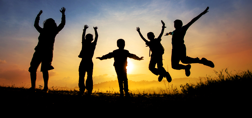 Silhouettes of children jumping in front of a sunset