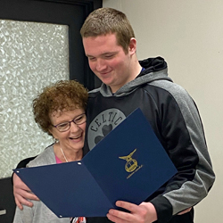 Chris Lee and Zack hug and smile while looking at a WRS completion certificate.