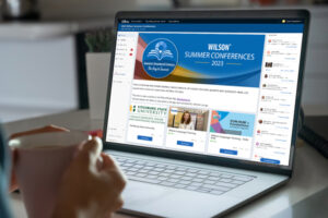 Conference on-demand laptop 600x400 Person's hands holding a mug in front of a laptop showing the Wilson Summer Conferences website