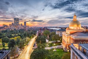 Massachusetts State House with Boston skyline at sunset