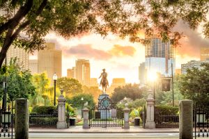 Boston Public Garden with Washington statue and city skyline at sunrise