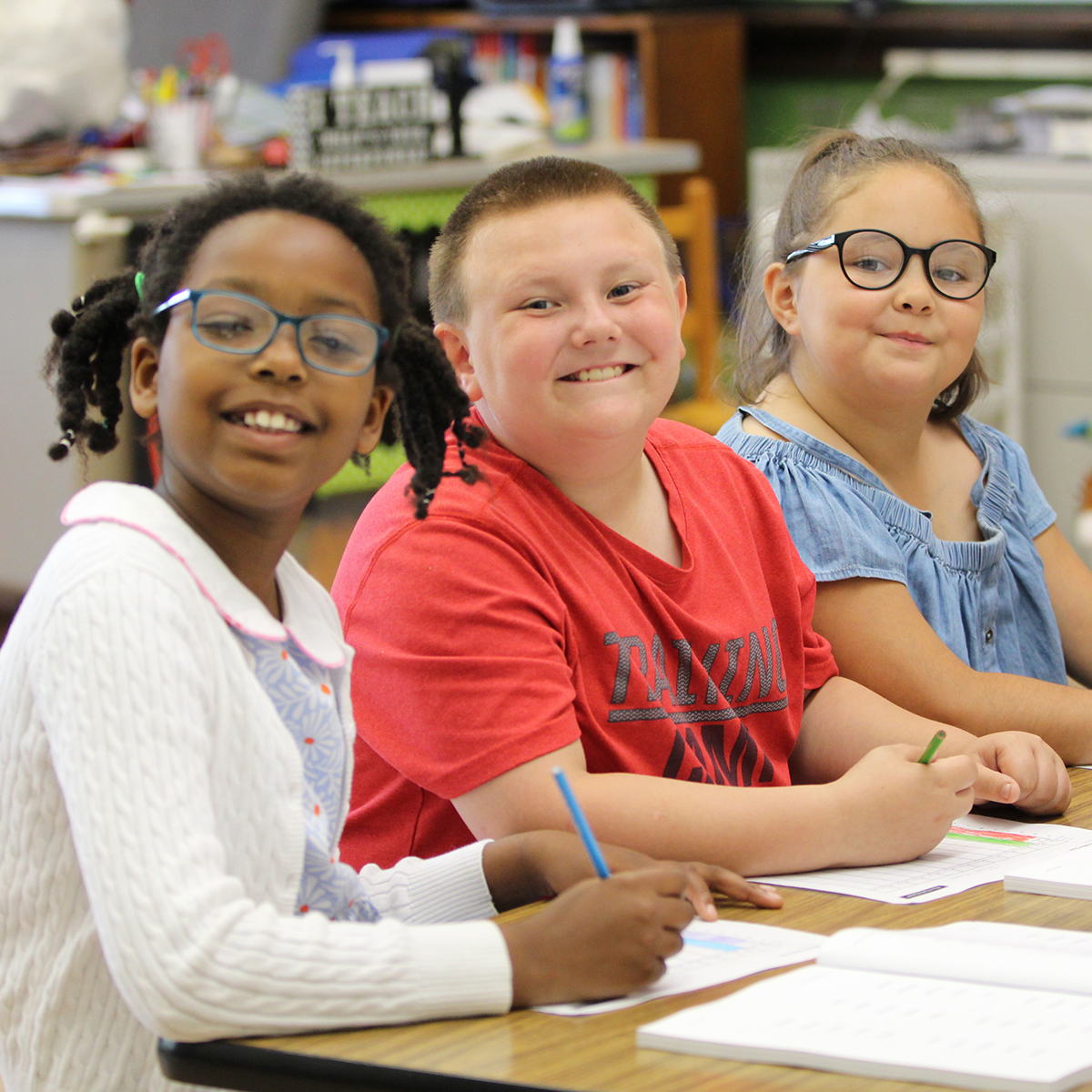 Three happy children in a classroom