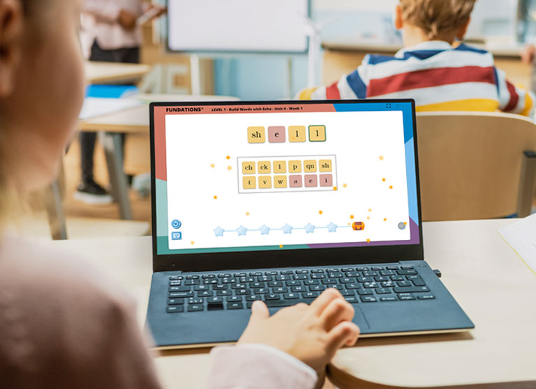 Young student at a laptop playing a word game on FUN HUB®.