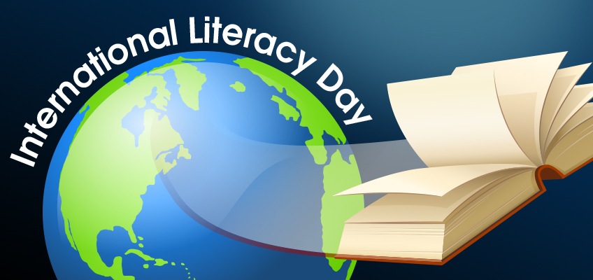 Illustration of an open book with pages turning into a sweeping arc around a globe. The text International Literacy Day curves along the top edge of the globe, set against a dark blue background.