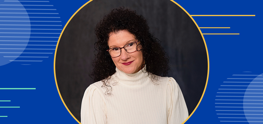 Woman with curly dark hair and glasses, wearing a white turtleneck, smiles against a dark background. The image has a blue border with abstract line designs.