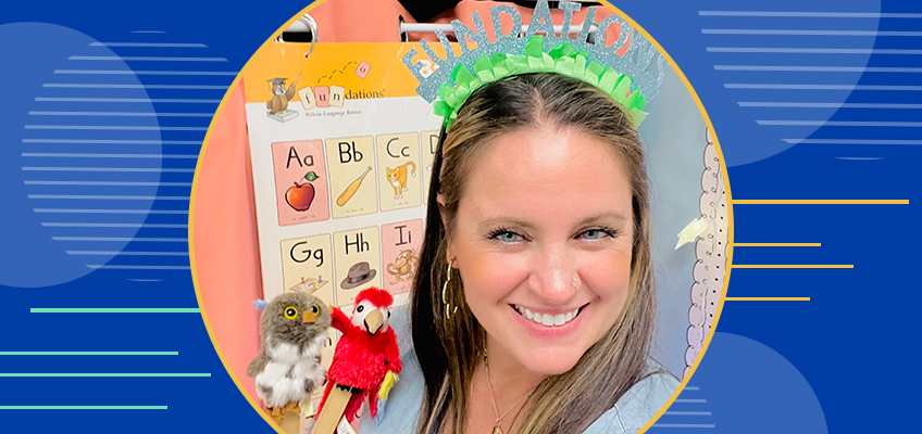 Smiling woman wearing a colorful crown holds plush owl and cardinal puppets. Behind her is an alphabet poster featuring letters and corresponding images. The background is blue with yellow geometric accents.