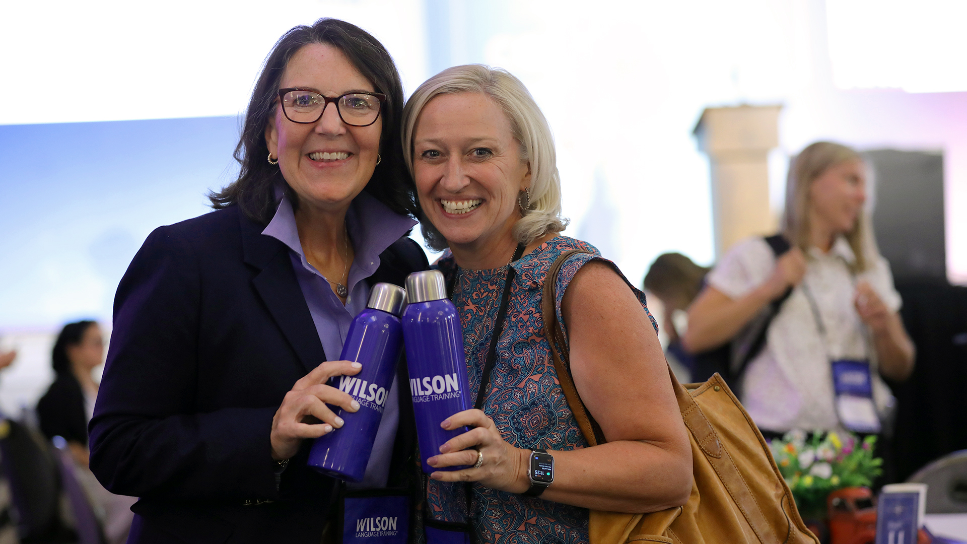 two women holding Wilson metal water bottles and smiling
