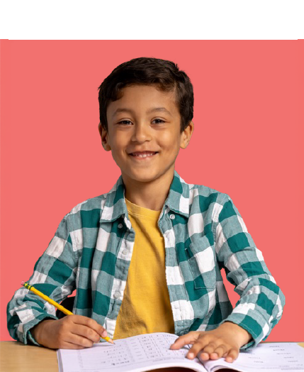 Young boy in a green plaid shirt smiles at the camera while holding a pencil and working in a workbook.