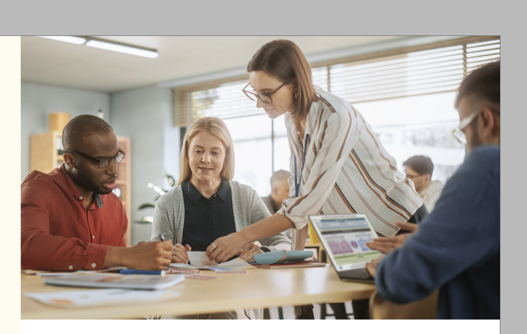 Team collaborating on project with tablet, papers, and pens on table.