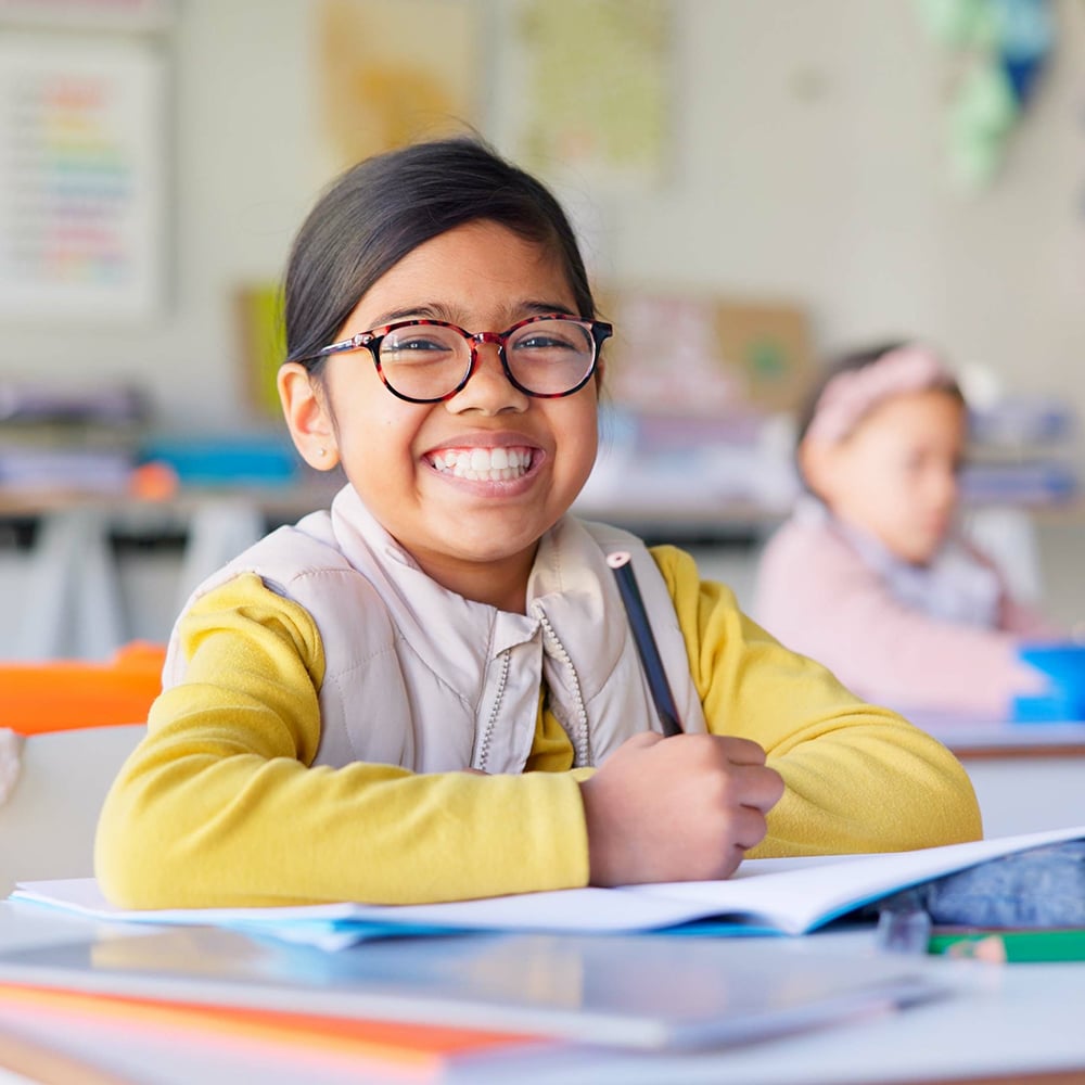 Smiling young student with glasses writing in a notebook