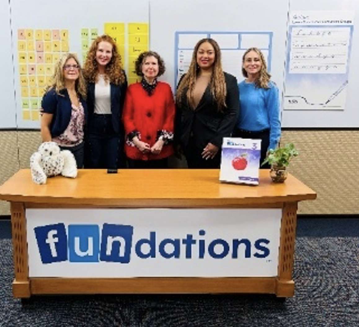 Foundations literacy team with a student workbook and owl plush