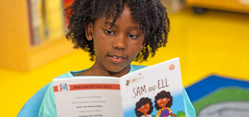 Young Black girl reads decodable book 