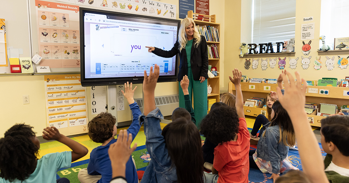 Teacher using Fundations® interactive whiteboard with students raising hands