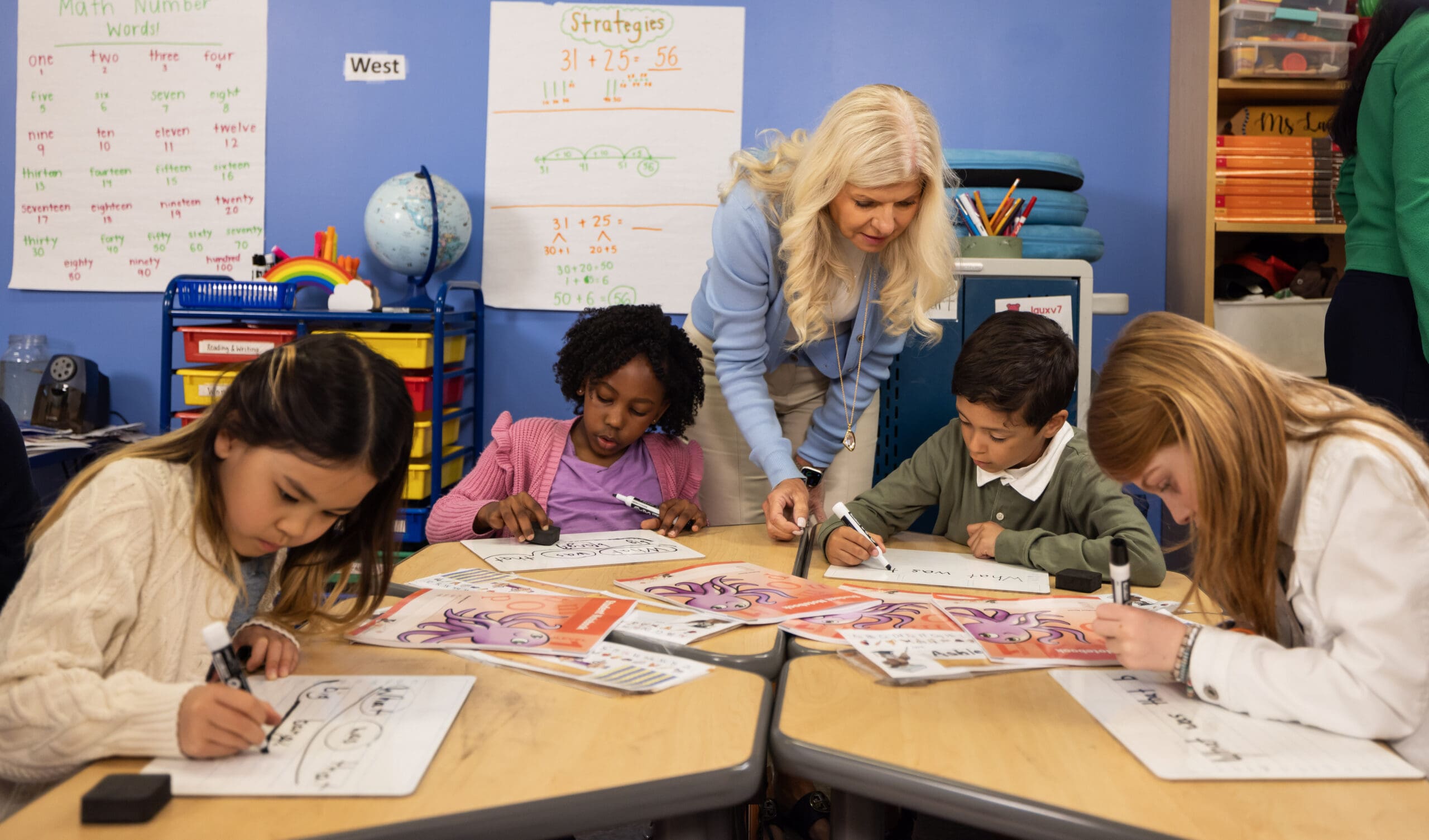 Teacher guiding young students in a Fundations K-3 math lesson with number charts.