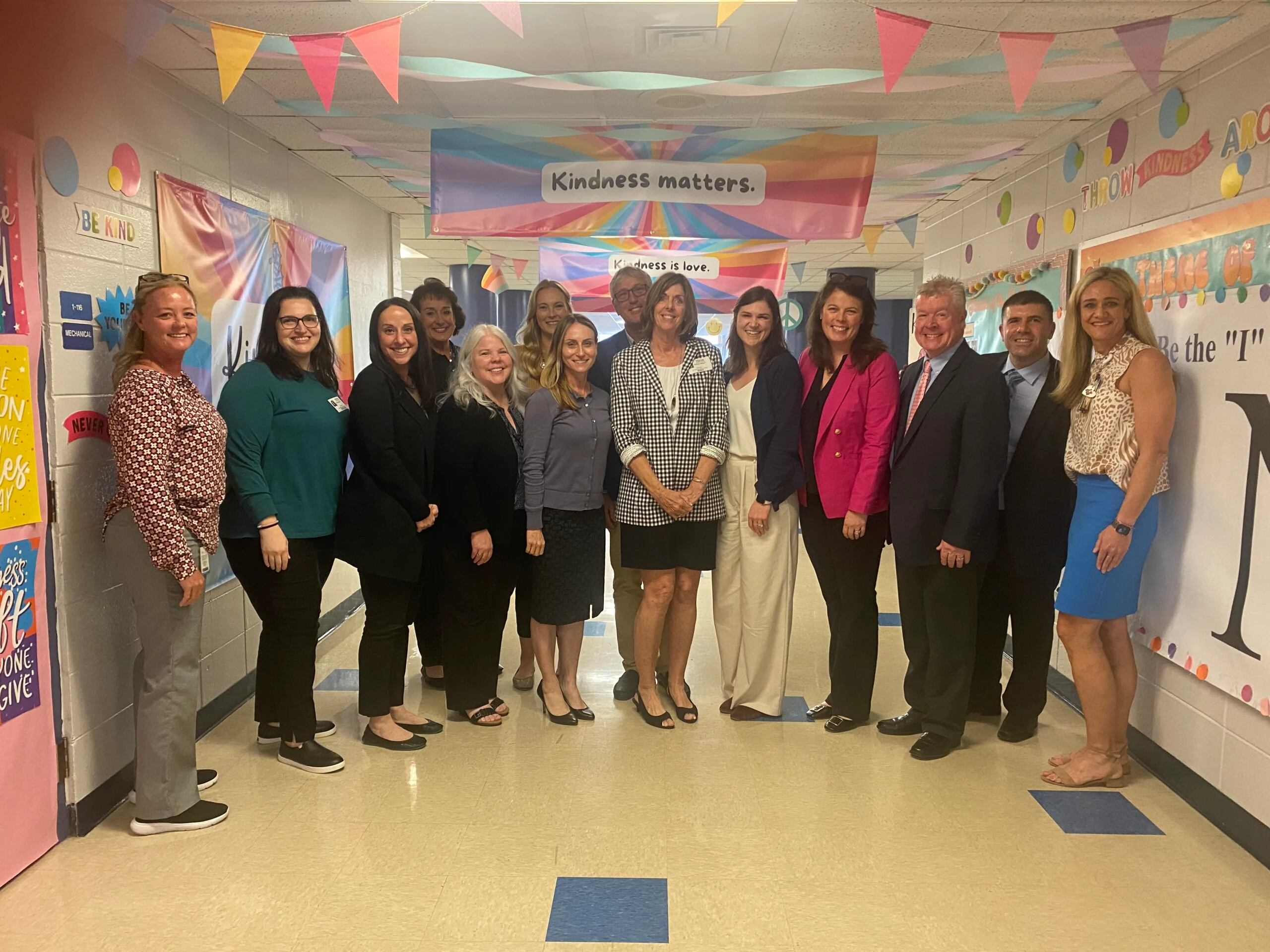 Group of educators in a school hallway with “Kindness matters” banner