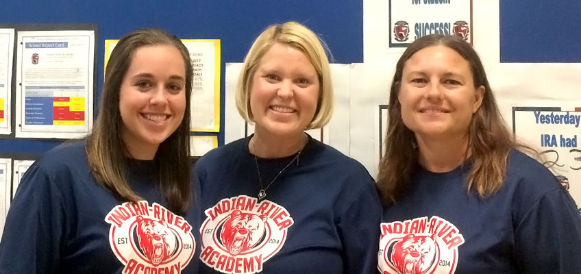 Three women in Indian River Academy t-shirts smiling.