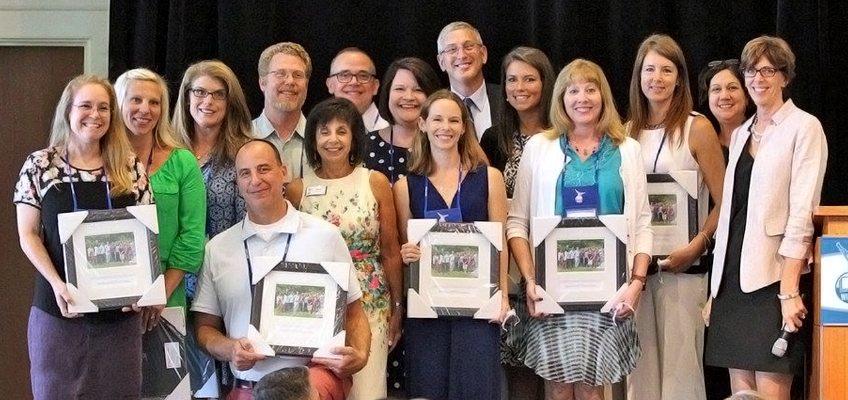 Group of people holding framed awards at an event, possibly a New Year celebration.