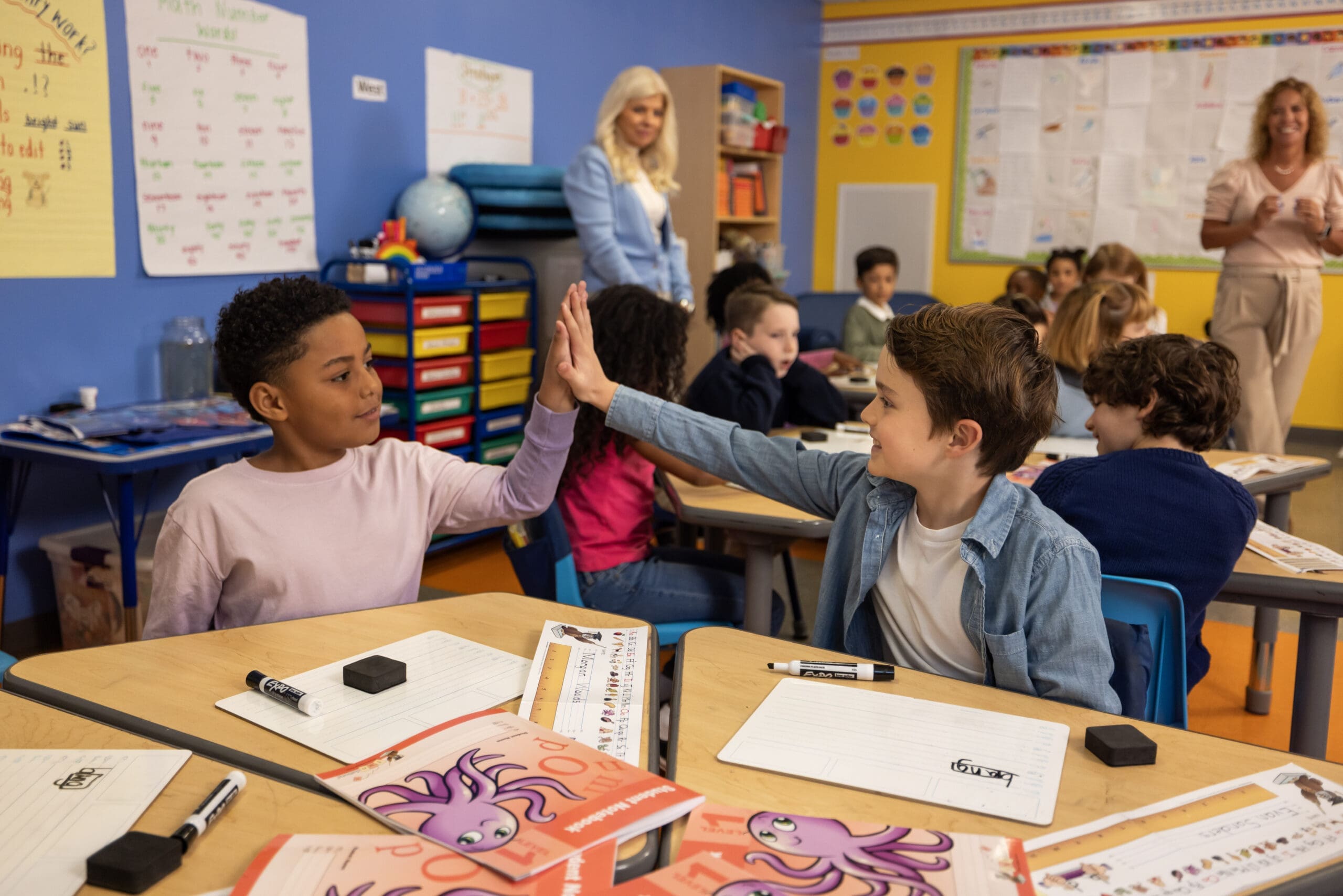 Two young students giving a high five in a bright classroom, Ready to Rise®