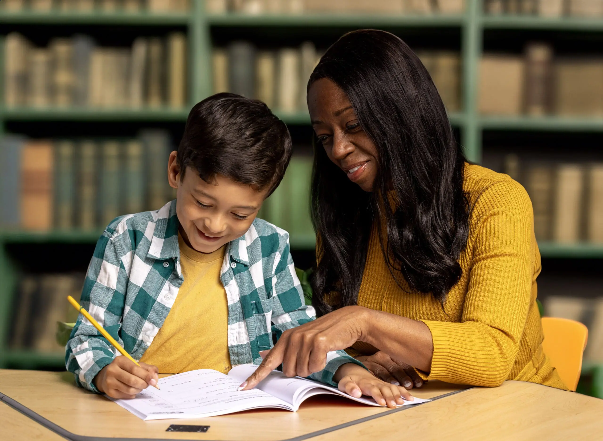 Teacher pointing at a book with a young student, illustrating Wilson Reading System instruction.