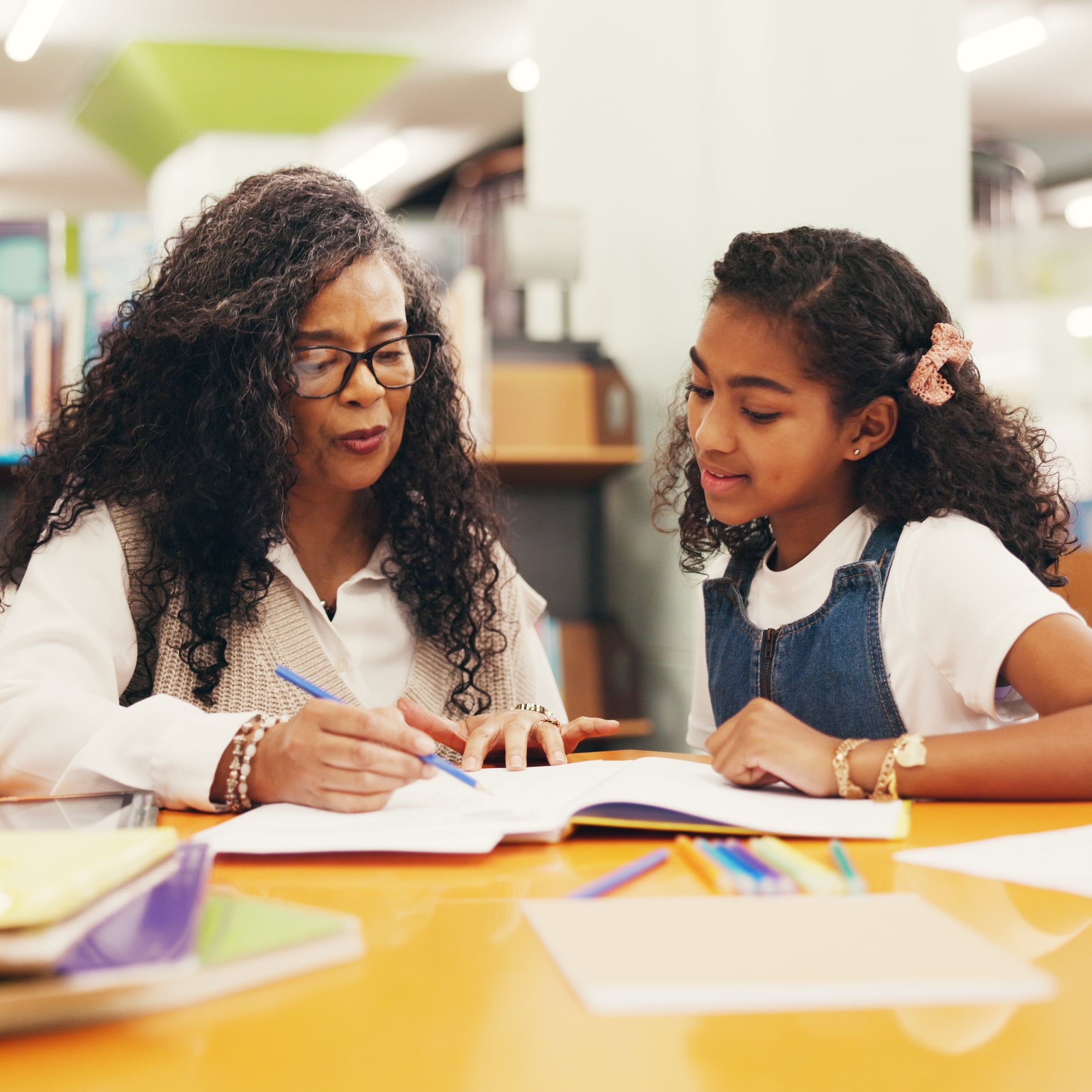 Teacher helps student with dyslexia reading in library