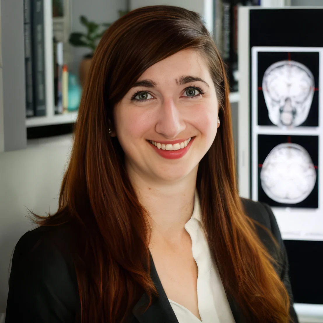 Woman smiling in front of brain scan images, possibly related to dyslexia research.